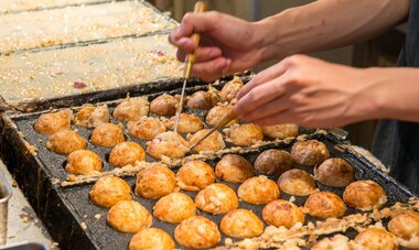 Délice japonais : le Takoyaki icône street food, rue Dōtonbori. Des Takoyaki en cuisson