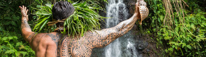 homme tatoué qui se tient devant une cascade