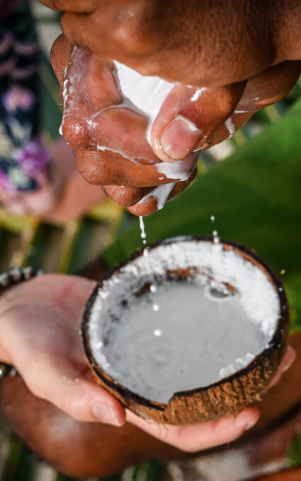 Photo d'une personne qui essore un tissu pour en faire couler le lait de coco